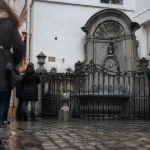 Manneken pis bruxelles : statue 55 cm près de la fontaine, visiteurs autour.
